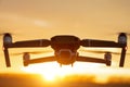 Unmanned quadcopter in flight with a digital camera at sunset. Drone silhouette at sunset