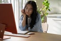 Tired bored Asian woman student falls asleep sits at computer in home interior during e-education