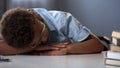 Unmotivated school boy sleeping on library desk near pile books, boring lesson