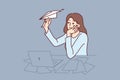 Unmotivated woman freelancer sitting at office desk with laptop and launching paper planes