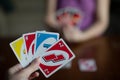 Playing american card game Uno, holding game cards in female hand.