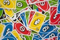 Uno game cards scattered all over the frame and hand of cards in the middle Royalty Free Stock Photo
