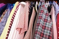 Unorganized clothes of different colors hanging in a wardrobe in mess close up, storage and order at home, cleaning and cluttering