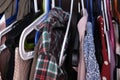 Unorganized clothes of different colors hanging in a wardrobe in mess close up, storage and order at home, cleaning and