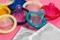 Unpacked condoms and packages on pink, closeup. Safe sex