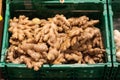 Unpacked loose ginger root bulbs in green plastic box on display in organic super market