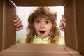 Unpacking cardboard box for kids. Happy little child boy is opening gift and looking inside cardboard box. Royalty Free Stock Photo