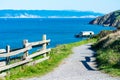 Unpaved hiking trail on cliff edge leading to lifeboat station at at Point Reyes Headlands. Scenic view of Drakes Bay calm blue