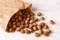 Unpeeled hazelnuts spilled out of a paper bag onto the white wood table. Nuts as an antioxidant and protein source for ketogenic