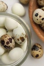 Unpeeled and peeled boiled quail eggs on white table