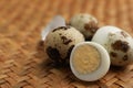 Unpeeled and peeled hard boiled quail eggs on wicker surface, closeup Royalty Free Stock Photo