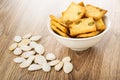 Unpeeled pumpkin seeds, bowl with cookies with pumpkin seeds on wooden table Royalty Free Stock Photo