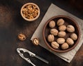 Unpeeled walnuts, nutcracker and peeled kernels on a brown background. Royalty Free Stock Photo