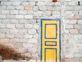 Unplastered concrete brick wall with yellow door.