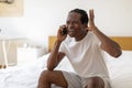 Unpleasant Call. Portrait Of Stressed Black Man Talking On Cellphone In Bedroom Royalty Free Stock Photo