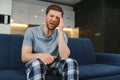 Unpleasant pain. Sad unhappy handsome man sitting on the sofa and holding his forehead while having headache. Royalty Free Stock Photo