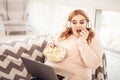 Unpleasant plus-size woman watching movie on her laptop