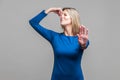 Unpleasant smell. Portrait of young woman in blue dress pinching her nose, showing stop gesture. studio shot isolated on gray