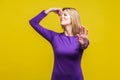 Unpleasant smell. Portrait of young woman in purple dress pinching her nose, showing stop gesture. studio shot isolated on yellow