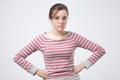 Unpleasant young lady in pulover holding hands on hips. Royalty Free Stock Photo