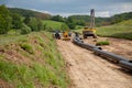 Unplugged gas pipeline in the coutryside diagonally from the right diagonally by photo with gas laying machines in the background