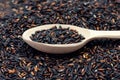 Unpolished black rice in wooden spoon. Long grain black rice, rice background. Black halthy rice