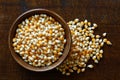 Unpopped popcorn in dark wooden bowl isolated on dark brown wood