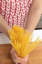 Unprepared spaghetti pasta. The girl in an apron holds in hands