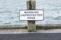 Unprotected edge warning sign at harbour port for car and vehicle safety preventing falling into the sea