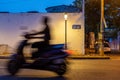 Unrecognisable man on a scooter, passing by a street sign at dusk, Pondicherry, India