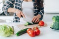 unrecognisable pregnant woman cook salad cutting cucumber on wooden board putting fresh vegetables and fruit on table in