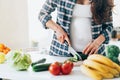 unrecognisable pregnant woman cook salad cutting cucumber on wooden board putting fresh vegetables and fruit on table in kitchen