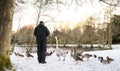 Unrecognisable senior man feeding wild birds , snow covered landscape