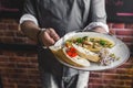 Unrecognisable waiter serving spicy chilli sauce shrimp dish with buttered bread. Restaurant service. Horizontal indoor