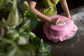 Unrecognisable woman in bakery decorating heart shaped wedding cake with pink fondant