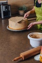 Unrecognisable woman decorating a delicious layered sponge cake with chocolate icing cream. Royalty Free Stock Photo