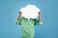 Unrecognizable african american young guy holding an empty speech bubble in front of his head, blue background Royalty Free Stock Photo