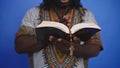 Unrecognizable African black man in traditional dress with rosary reading the Holy Bible Royalty Free Stock Photo