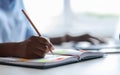 Unrecognizable african female secretary taking notes while working on laptop in office Royalty Free Stock Photo