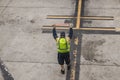 Unrecognizable airport worker gets ready to guide an airplne in to land with red flasher sticks