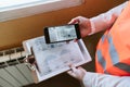 Unrecognizable architect woman in construction site using mobile phone holding blueprints