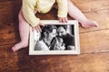 Unrecognizable baby holding family photo. Fathers day. Royalty Free Stock Photo
