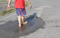 unrecognizable barefoot child joyfully walks in a transparent puddle on the pavement after rain
