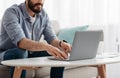 Unrecognizable bearded man working on pc, typing text or programming code on computer keyboard