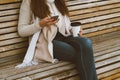 Unrecognizable beautiful young girl drinking coffee, tea from plastic mug in autumn, winter and talking on mobile phone. Woman Royalty Free Stock Photo