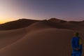 Unrecognizable Berber man walking on a dreamy desert at Twilight of dawn. Desert dune of Erg Chigaga, at the gates of the Sahara. Royalty Free Stock Photo