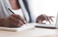 Unrecognizable female employee taking notes while working on laptop in office Royalty Free Stock Photo