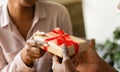 Unrecognizable black guy giving his girlfriend birthday gift at cafe, closeup of hands