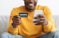 Unrecognizable black guy holding cellphone and credit card Royalty Free Stock Photo