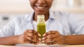 Unrecognizable Black Lady Posing With Green Smoothie Bottle Indoors, Cropped